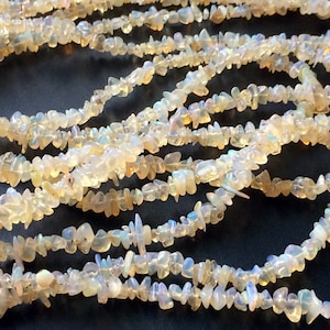 May include: A strand of white opal chip beads. The beads are irregular in shape and have a translucent, iridescent quality.