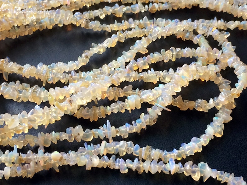 May include: A strand of white opal chip beads. The beads are irregular in shape and have a translucent, iridescent quality.