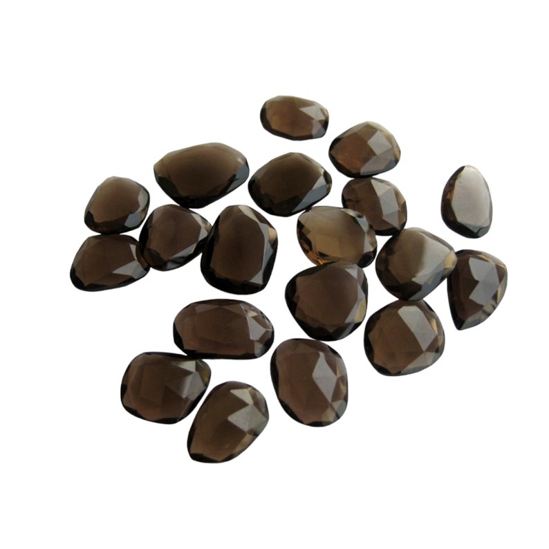 May include: A collection of 17 smoky quartz gemstones, each with a unique, faceted shape. The stones are a dark brown color and have a translucent appearance.