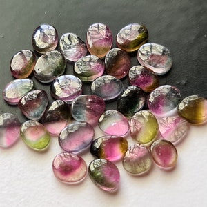 Peut inclure: Une collection de pierres pr&eacute;cieuses ovales multicolores. Les pierres sont un m&eacute;lange de rose, de vert et de noir.