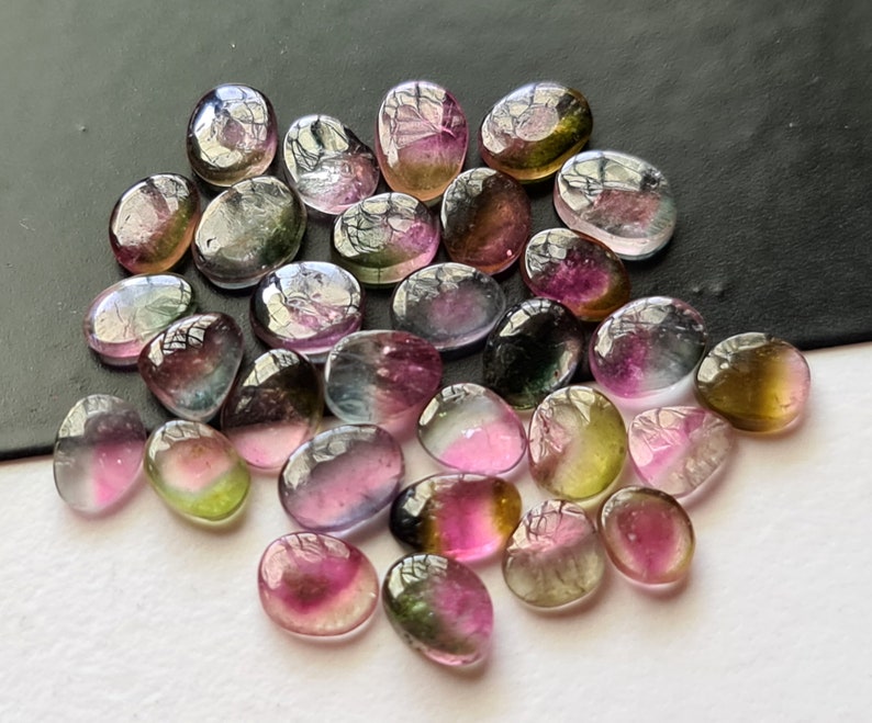 Peut inclure: Une collection de pierres pr&eacute;cieuses ovales multicolores. Les pierres sont un m&eacute;lange de rose, de vert et de noir.