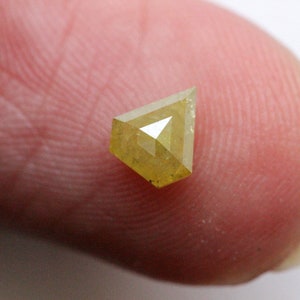 May include: A yellow diamond with a triangular shape, set on a finger.