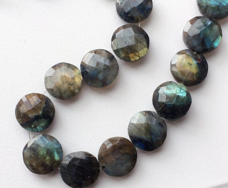 May include: A strand of round, faceted labradorite beads in shades of green, blue, and gold. The beads are strung on a clear thread.