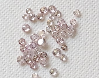 Puede incluir: Una colección de diamantes sueltos, facetados, de talla rosa. Los diamantes son de color rosa pálido y tienen una variedad de tamaños.