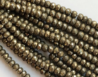 May include: A strand of faceted pyrite beads, each bead is a dark gold color and has a rough, irregular surface.