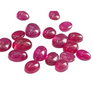 May include: A collection of oval-shaped, cabochon cut, ruby gemstones. The rubies are a deep, rich red color and have a smooth, polished finish.