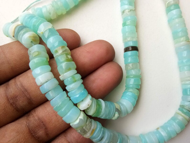 May include: A strand of light blue opal beads, with a silver spacer bead, for jewelry making.