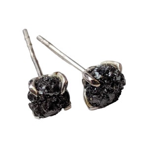 May include: A pair of silver stud earrings with black rough diamond stones.