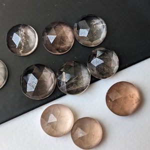 Puede incluir: Ocho cabujones redondos facetados de cuarzo transparente y ahumado. Los cabujones tienen un di&aacute;metro aproximado de 2,5 cm.