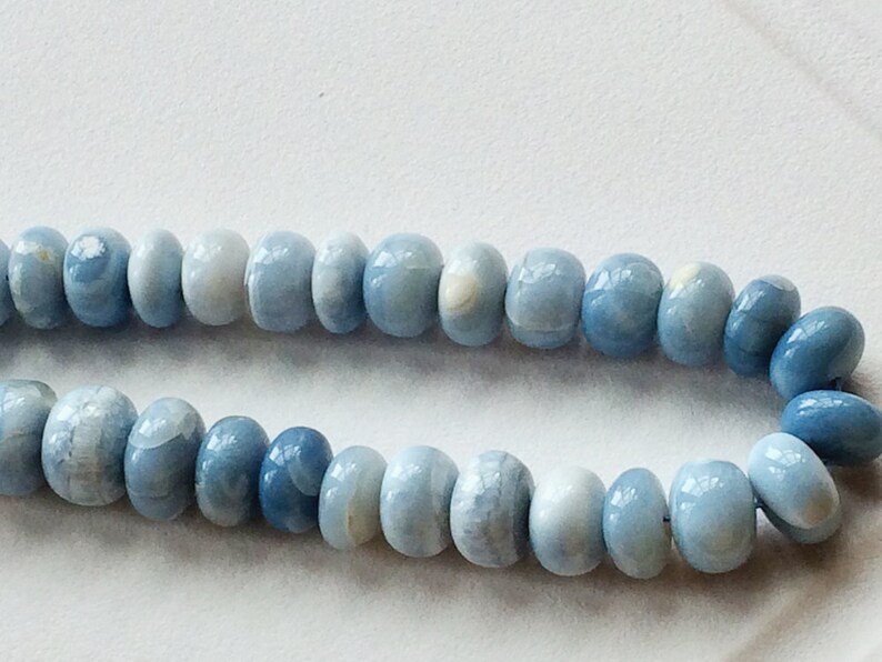 May include: A strand of light blue opal beads. The beads are round and have a smooth, polished finish.