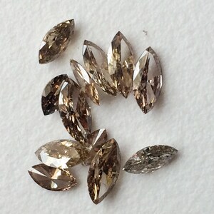 May include: A group of 10 brown marquise-shaped diamonds, some with a more golden hue, others with a more gray hue.