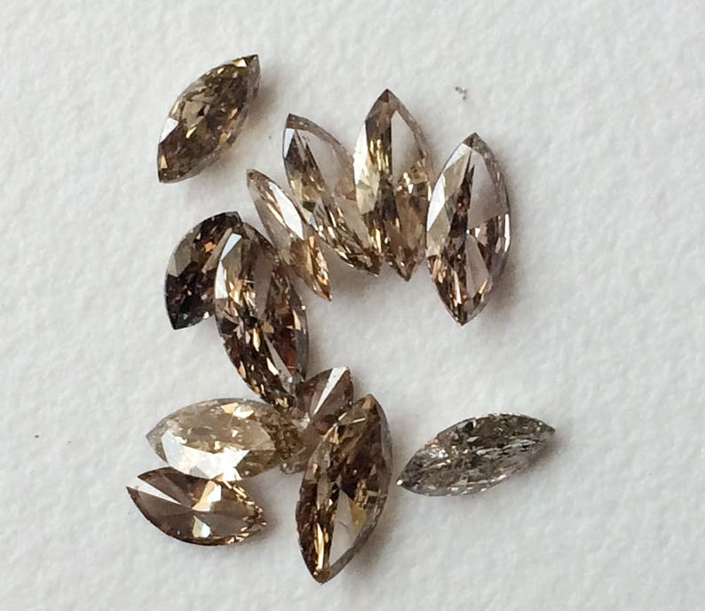 May include: A group of 10 brown marquise-shaped diamonds, some with a more golden hue, others with a more gray hue.