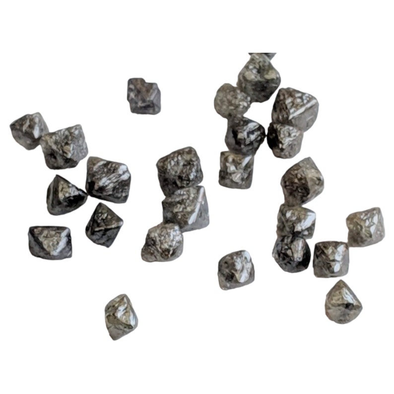 Puede incluir: Una colecci&oacute;n de peque&ntilde;os diamantes negros en bruto. Los diamantes est&aacute;n dispersos sobre un fondo blanco.