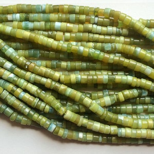 May include: A strand of green and yellow jade beads. The beads are small and round, and they are strung on a thin wire. The beads are all different sizes and shapes, and they have a natural, organic look.