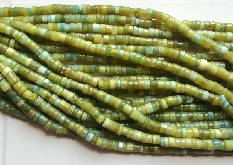May include: A strand of green and yellow jade beads. The beads are small and round, and they are strung on a thin wire. The beads are all different sizes and shapes, and they have a natural, organic look.