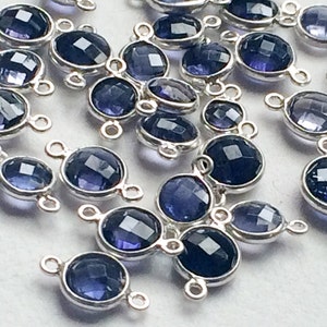 Könnte beinhalten: Eine Gruppe von silberfarbenen Metallverbindern mit runden, facettierten Amethyst-Edelsteinen. Die Verbinder haben an jeder Seite zwei Schlaufen, so dass sie an andere Schmuckstücke befestigt werden können.