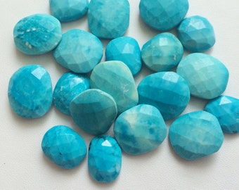 Puede incluir: Una colección de cabujones de turquesa, cada uno con una forma facetada única. Las piedras son de un color azul verdoso vibrante y tienen un acabado liso y pulido.