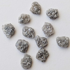 K&ouml;nnte beinhalten: Eine Sammlung von zehn rohen, grauen Diamanten. Die Diamanten sind in verschiedenen Gr&ouml;&szlig;en und Formen, mit einer rauen, unpolierten Oberfl&auml;che.