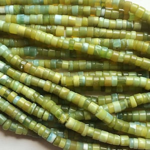 May include: A strand of green and yellow gemstone beads. The beads are small and round, and they have a smooth, polished finish.