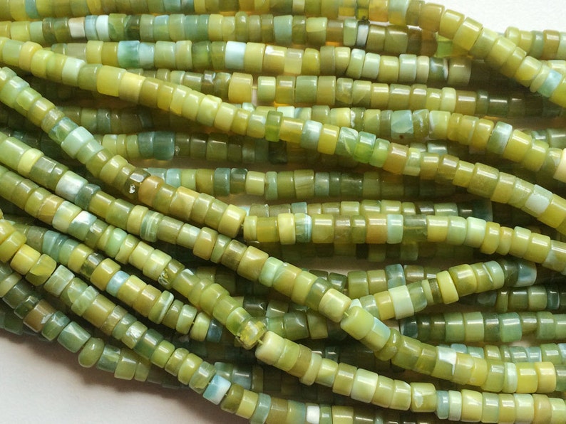 May include: A strand of green and yellow gemstone beads. The beads are small and round, and they have a smooth, polished finish.