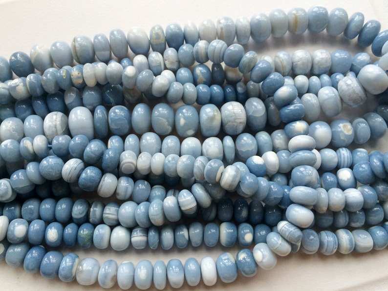 May include: A strand of light blue and white agate beads. The beads are oval shaped and have a smooth, polished finish.