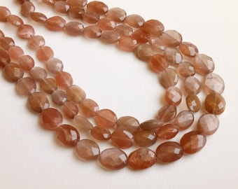 May include: A strand of oval-shaped sunstone beads in shades of orange and brown. The beads have a faceted finish and are strung on a clear thread.