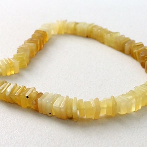 May include: A strand of yellow opal beads, each bead is a rectangular shape with a slightly irregular, faceted surface.