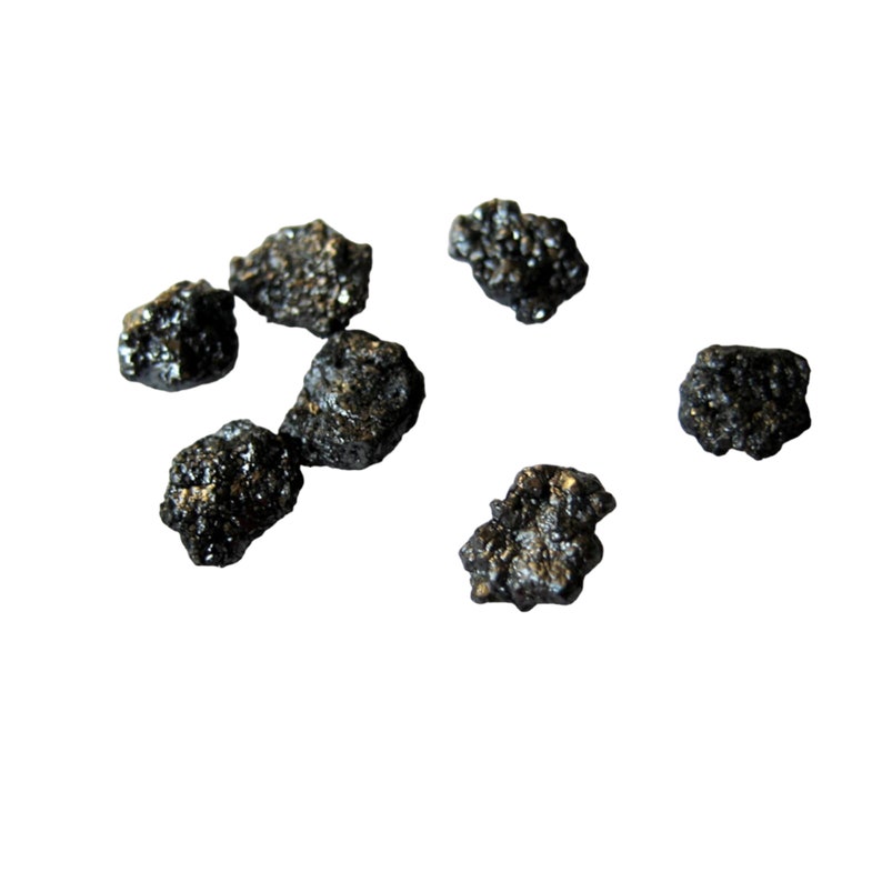 May include: A collection of seven small, black, irregularly shaped stones. The stones have a rough, textured surface.