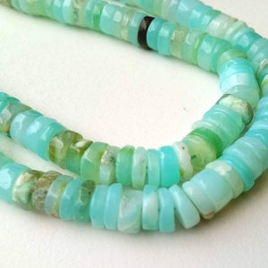May include: A strand of turquoise blue opal beads, with some beads having a green hue, arranged in a double row.