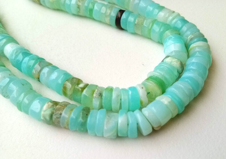 May include: A strand of turquoise blue opal beads, with some beads having a green hue, arranged in a double row.