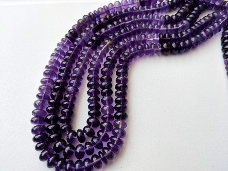 May include: A strand of purple amethyst beads, with multiple strands of beads layered on top of each other. The beads are round and have a smooth, polished finish.