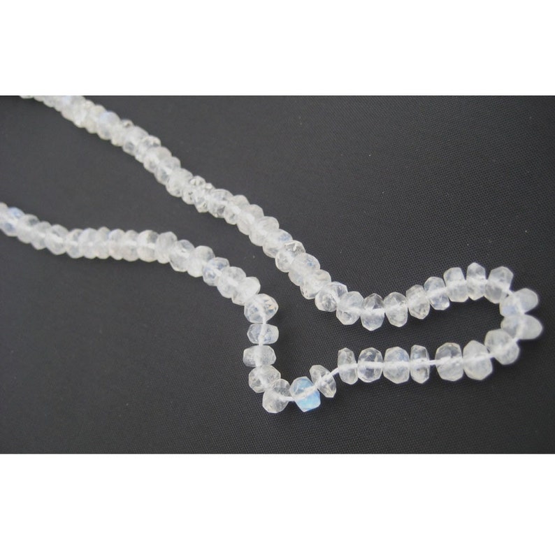 Peut inclure: Un collier de perles de pierre de lune blanche, chaque perle est facet&eacute;e et pr&eacute;sente une l&eacute;g&egrave;re qualit&eacute; iris&eacute;e.