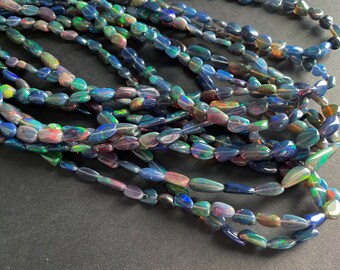 May include: A strand of iridescent black opal beads, each bead is a unique teardrop shape with a smooth, polished finish.