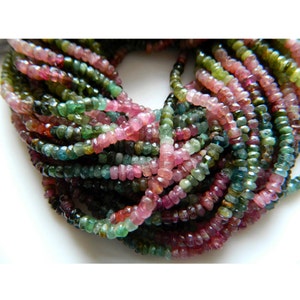 May include: A strand of multi-colored tourmaline beads. The beads are faceted and have a mix of pink, green, and black colors.