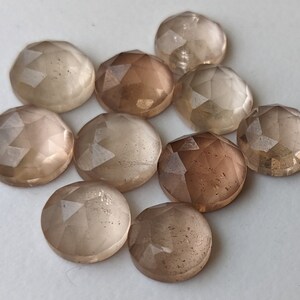 Puede incluir: Diez piedras preciosas redondas, facetadas, transl&uacute;cidas, de color marr&oacute;n claro. Las piedras tienen una calidad ligeramente iridiscente.