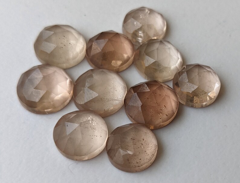 Puede incluir: Diez piedras preciosas redondas, facetadas, transl&uacute;cidas, de color marr&oacute;n claro. Las piedras tienen una calidad ligeramente iridiscente.