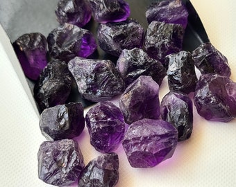 Peut inclure: Une collection de cristaux d'améthyste bruts de différentes tailles et formes. Les cristaux sont d'une couleur violet foncé et ont une texture naturelle et rugueuse.