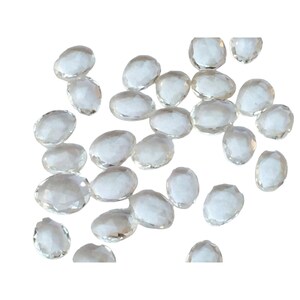 Peut inclure: Une collection de pierres pr&eacute;cieuses ovales facett&eacute;es et transparentes. Les pierres sont &eacute;parpill&eacute;es sur un fond blanc.