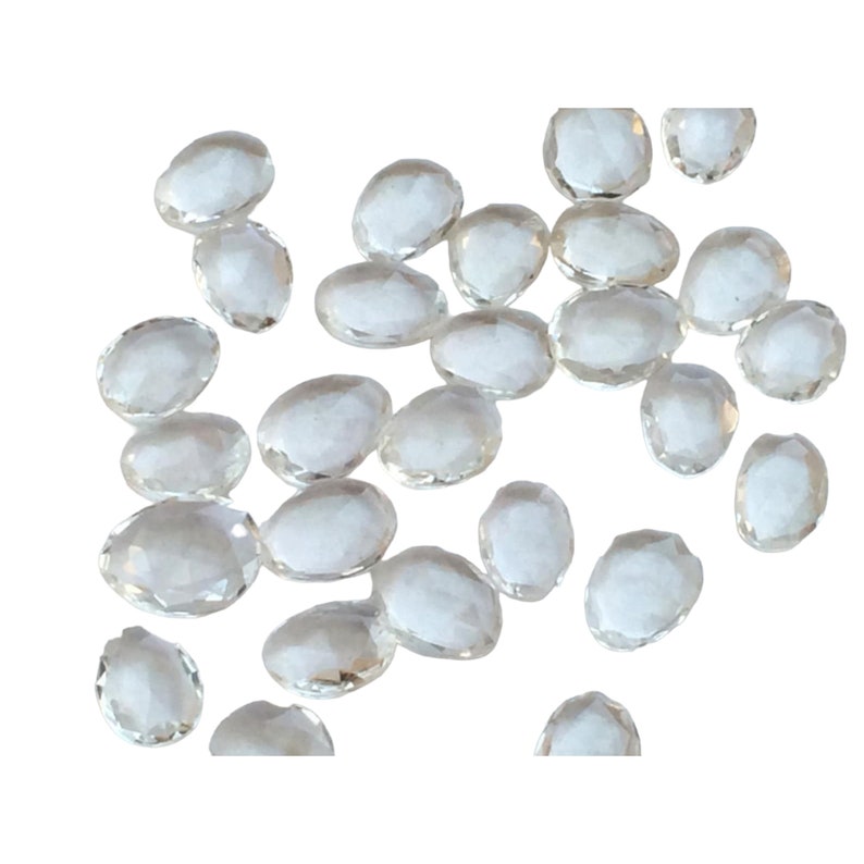 Peut inclure: Une collection de pierres pr&eacute;cieuses ovales facett&eacute;es et transparentes. Les pierres sont &eacute;parpill&eacute;es sur un fond blanc.
