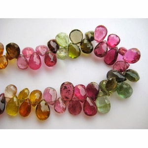 May include: A strand of faceted gemstone beads in shades of green, pink, and brown. The beads are teardrop shaped and have a polished finish.