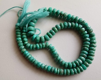 May include: A strand of turquoise gemstone beads, each bead is faceted and has a light blue-green color. The beads are strung on a thin cord and have a tassel at one end.