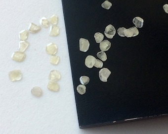 May include: A collection of small, clear, faceted diamonds on a white and black background. The diamonds are arranged in a circle on the white side and scattered on the black side.