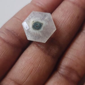 May include: A hexagonal, clear, white, and gray gemstone with a dark gray and white pattern in the center.