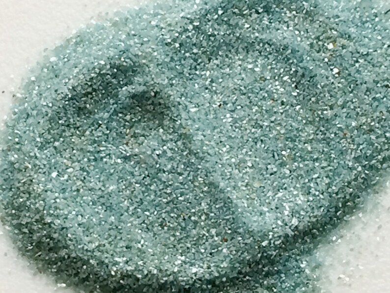 May include: A close-up of teal blue glitter. The glitter is very fine and has a slight shimmer.