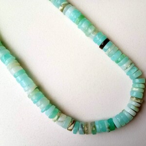 May include: A light blue opal bead necklace with a variety of sizes and shapes. The beads are strung on a clear thread and have a natural, iridescent finish.