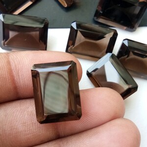 以下が含まれることがあります： 長方形のエメラルドカットの煙水晶の宝石が8つ。宝石は濃い茶色で、滑らかで磨かれた仕上げになっています。