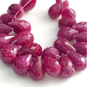 Peut inclure: Un brin de perles de rubis facettées en forme de goutte. Les perles sont d'une couleur rouge foncé et riche et sont enfilées sur un fil d'argent.