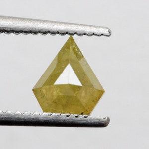 May include: A yellow diamond with a triangular shape, held by tweezers.
