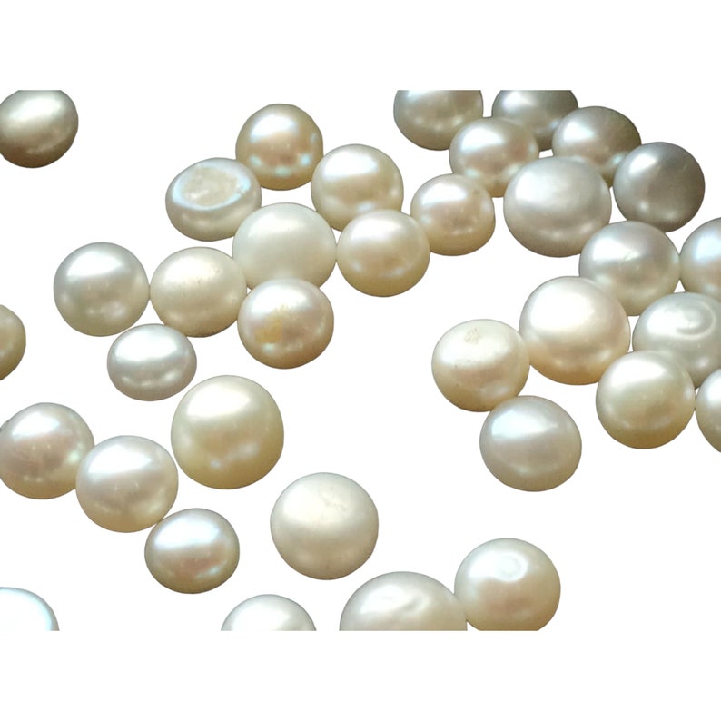 May include: A collection of white round pearls, scattered on a white background.