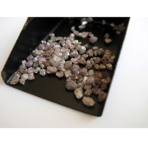 May include: A small black tray filled with a large quantity of rough, unpolished, pink and brown diamonds.